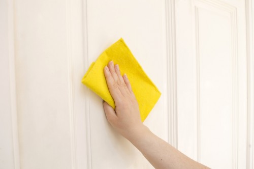 hand cleaning a door white with a yellow cloth